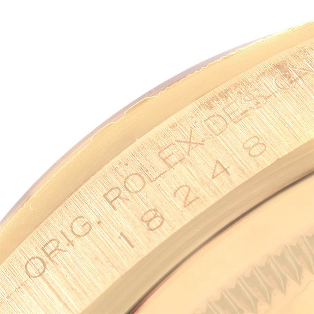 This close-up image of the Rolex President 18248 Men's Yellow Gold Silver Dial 18248 Men's Yellow Gold Silver Dial model watch shows the engraved bezel and part of the case side.