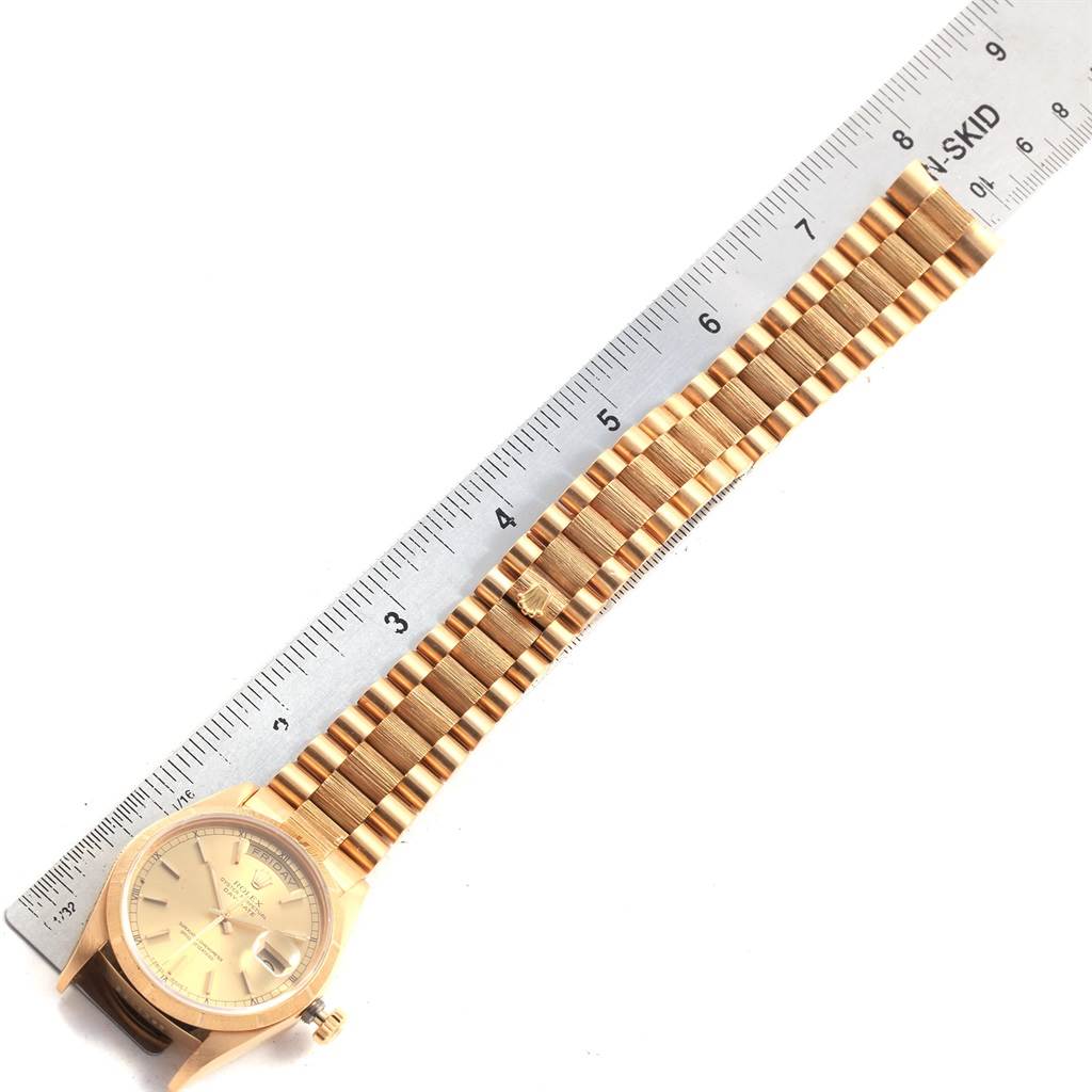 The image shows a Rolex President 18078 Men
s Yellow Gold Champagne Dial 18078 Men
s Yellow Gold Champagne Dial model watch laid flat against a ruler, highlighting its bracelet and dial from a top-down view.