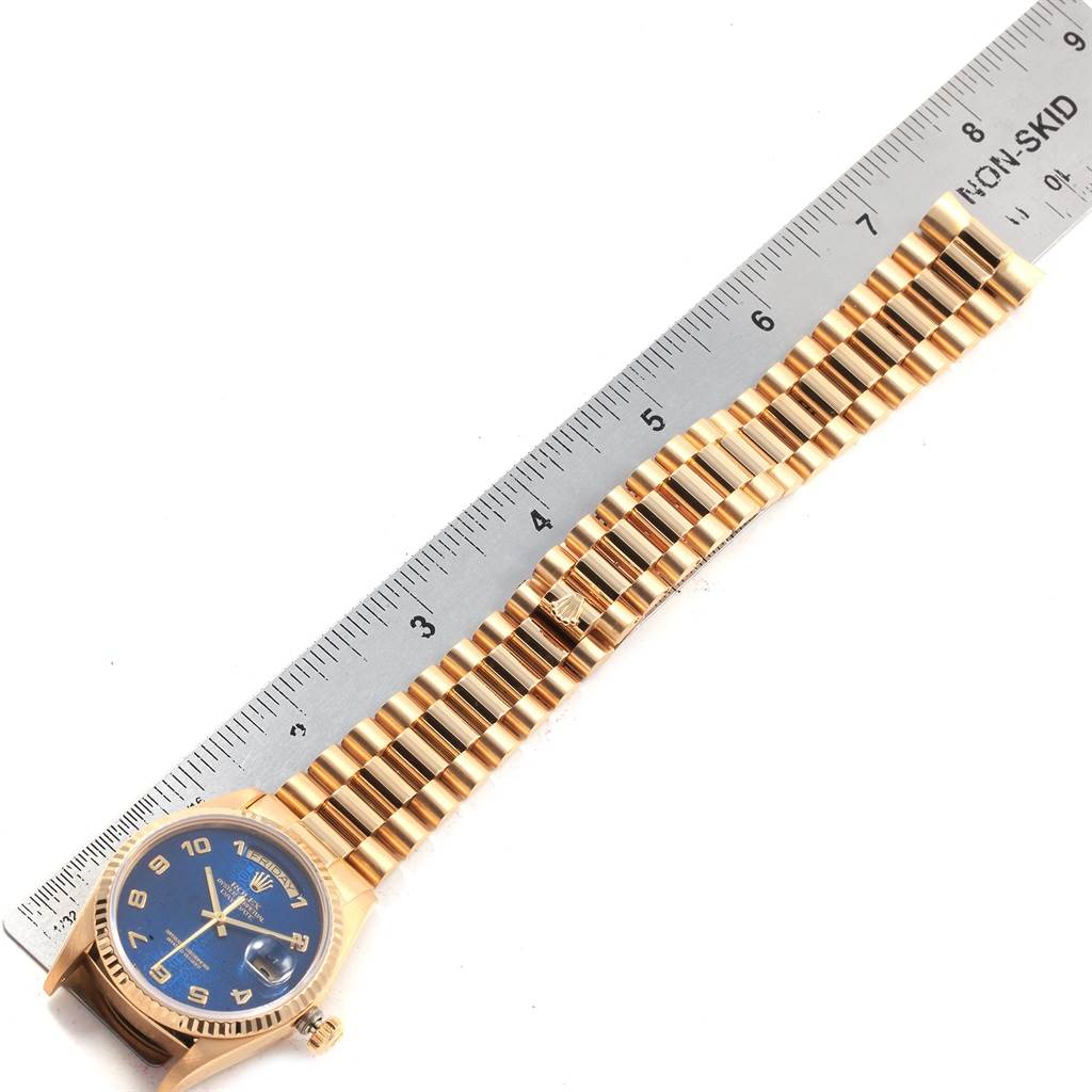 The Rolex President 18038 Men
s Yellow Gold Blue Dial 18038 Men
s Yellow Gold Blue Dial model watch is shown from a top-down angle, highlighting the face, bezel, and bracelet next to a ruler for scale.