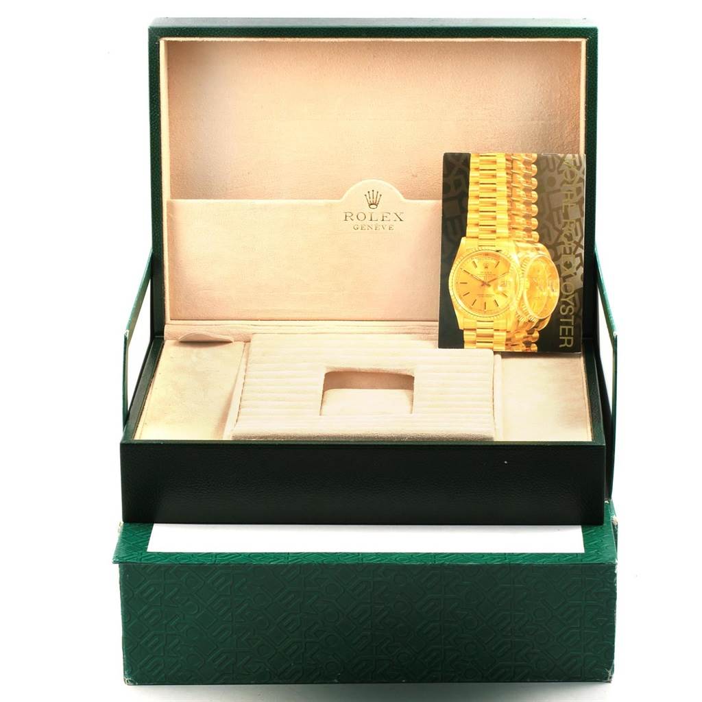 The image shows an open box for the Rolex President 118338 Men
s Yellow Gold Champagne Dial 118338 Men
s Yellow Gold Champagne Dial model watch with its interior packaging and a booklet with an image of the watch.