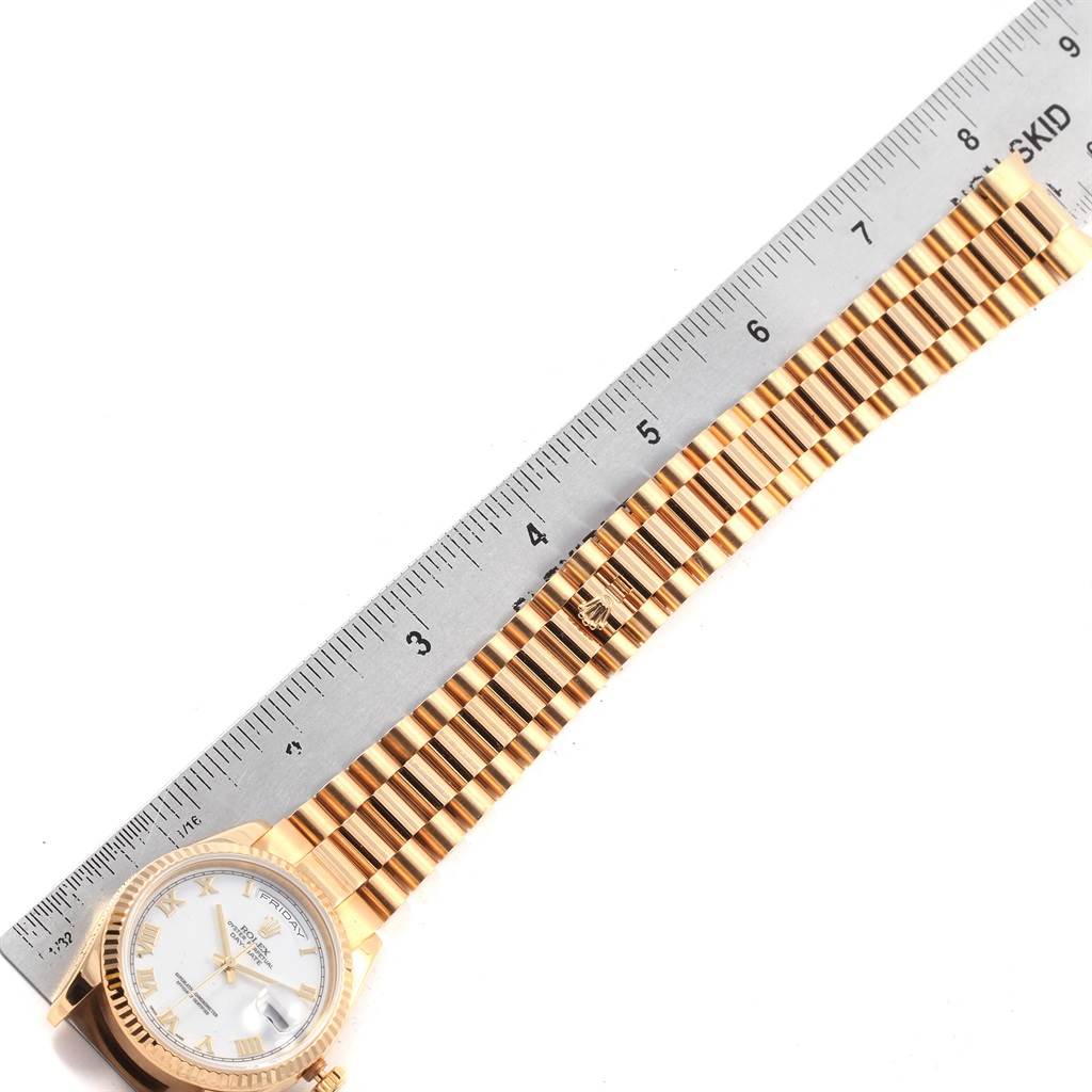 The image shows a Rolex President 118238 Men
s Yellow Gold White Dial 118238 Men
s Yellow Gold White Dial watch lying flat next to a ruler, displaying its band and face straight on.