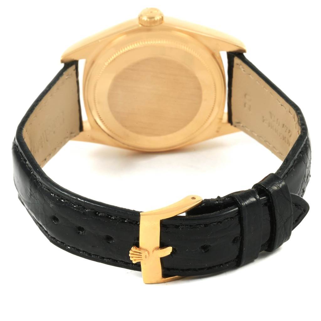 The image shows the back view of a Rolex President 18038 Men
s Yellow Gold Champagne Dial 18038 Men
s Yellow Gold Champagne Dial model watch, highlighting the case back and black leather strap with a gold clasp.