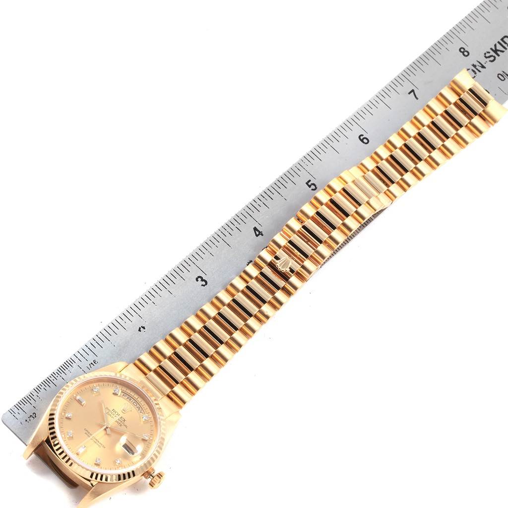 The image shows a Rolex President 18238 Men
s Yellow Gold Champagne Dial 18238 Men
s Yellow Gold Champagne Dial model watch laid flat next to a ruler, displaying its dial, band, and clasp.
