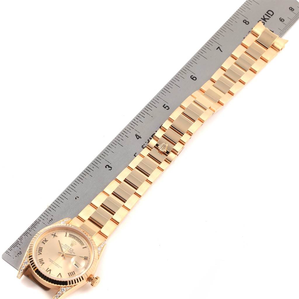 The image shows a Rolex President 118338 Men
s Yellow Gold Champagne Dial 118338 Men
s Yellow Gold Champagne Dial model watch and its bracelet laid next to a ruler from a top-down angle.