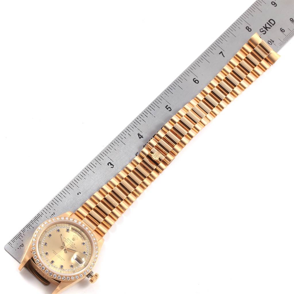 The image shows a Rolex President 18048 Men
s Yellow Gold Champagne Dial 18048 Men
s Yellow Gold Champagne Dial model watch with a gold bracelet and diamond bezel, placed next to a measuring ruler.
