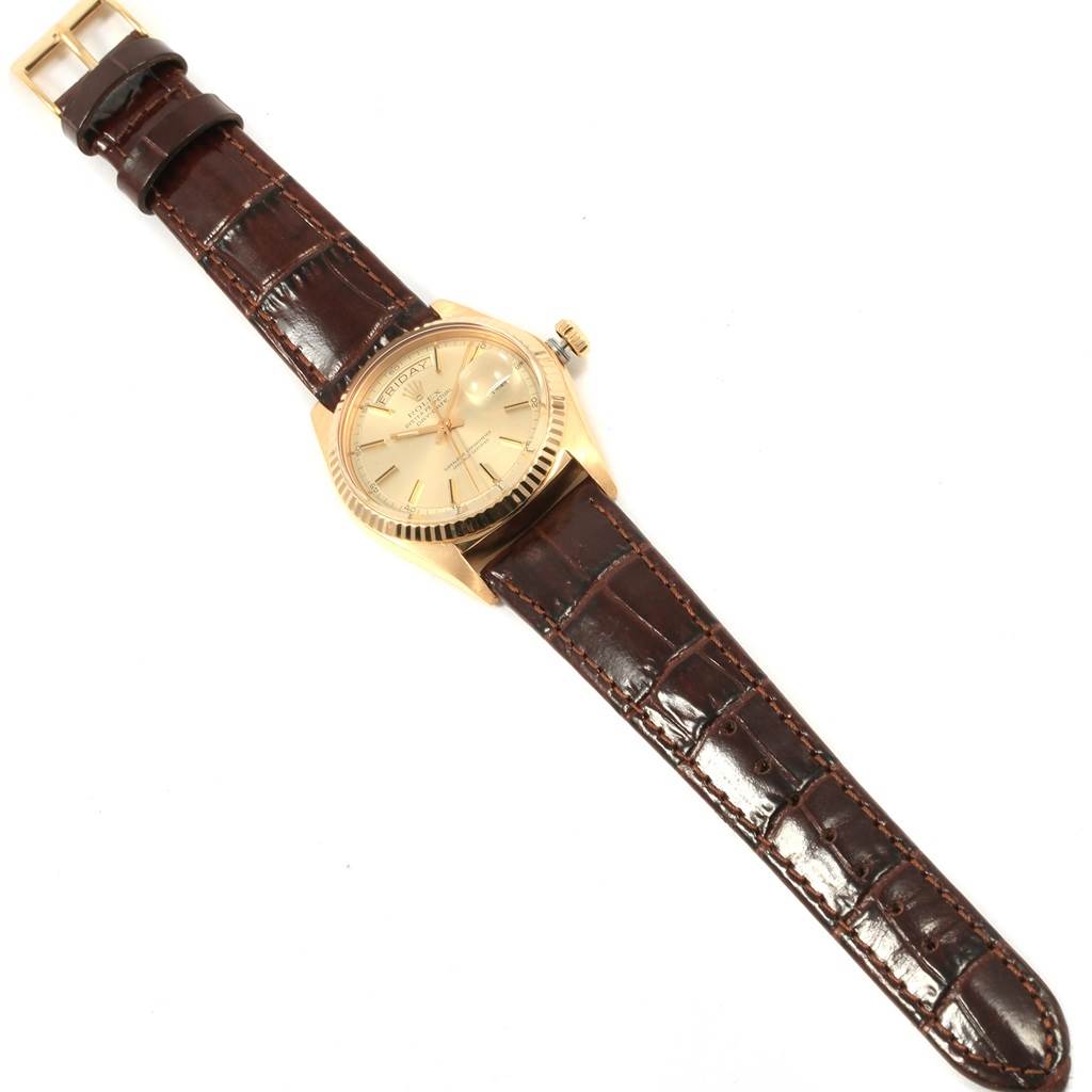 The image shows a Rolex President 1804 Men
s Yellow Gold Champagne Dial 1804 Men
s Yellow Gold Champagne Dial model watch with a gold case and a brown leather strap, viewed from a top-down angle.