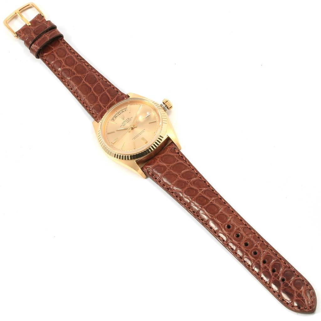 The President model by Rolex is shown from a top-down angle, featuring its face, bezel, crown, and brown leather strap.