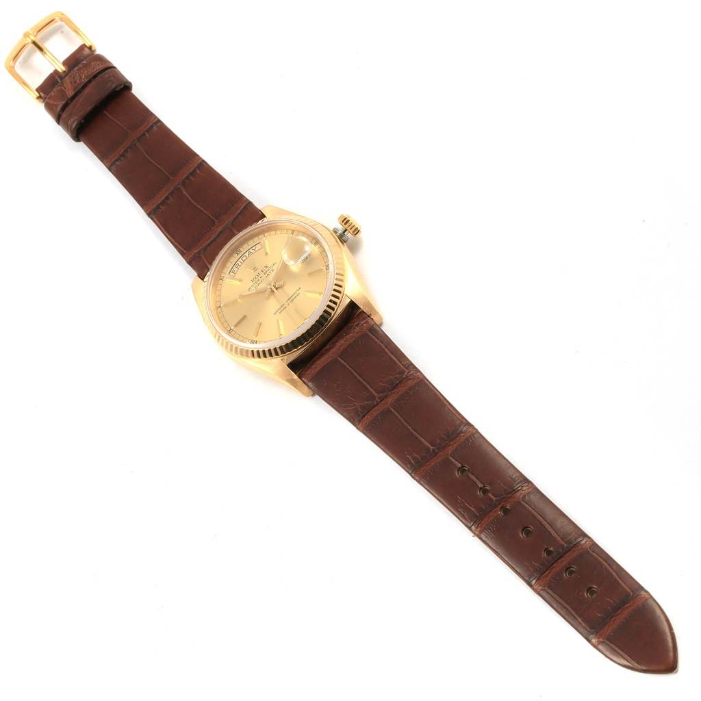 The image shows a Rolex President 18038 Men
s Yellow Gold Champagne Dial 18038 Men
s Yellow Gold Champagne Dial model watch viewed from above, featuring a gold dial and brown leather strap.