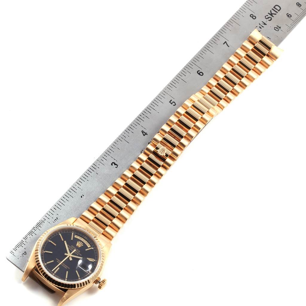 This image shows the full view of a Rolex President 18238 Men
s Yellow Gold Black Dial 18238 Men
s Yellow Gold Black Dial model watch, including its face, band, and a ruler for scale.