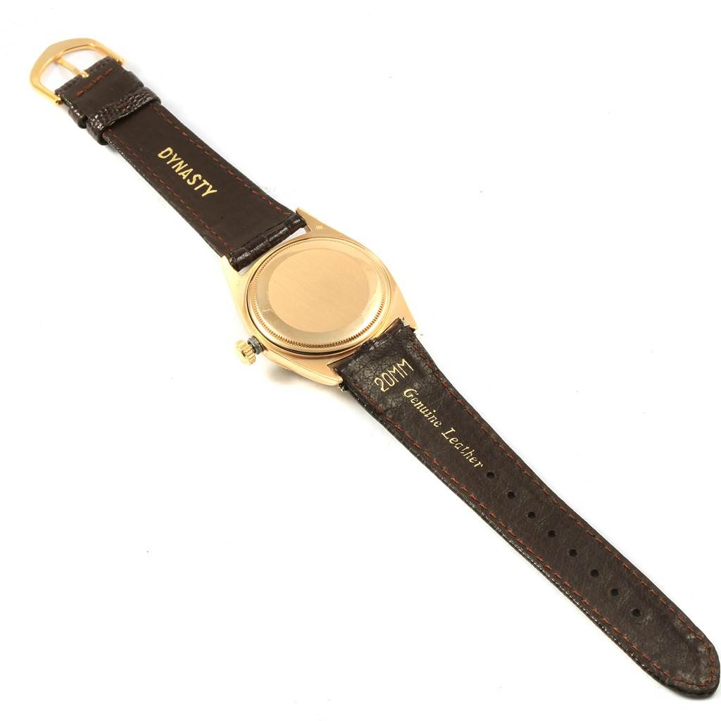 This image shows the back of a Rolex President 1807 Men
s Yellow Gold White Dial 1807 Men
s Yellow Gold White Dial watch with a dark leather strap from a top-down angle.