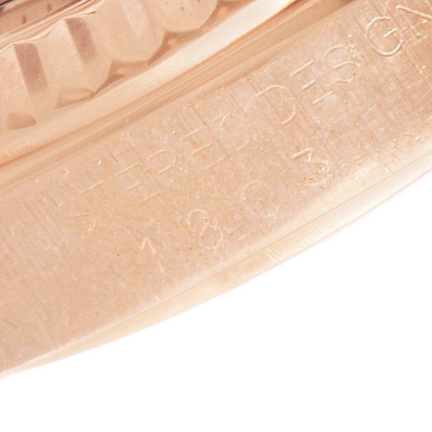 This close-up image of a Rolex President 1803 Men's Rose Gold Pink Dial 1803 Men's Rose Gold Pink Dial watch shows part of the bezel and an engraved section of the band.
