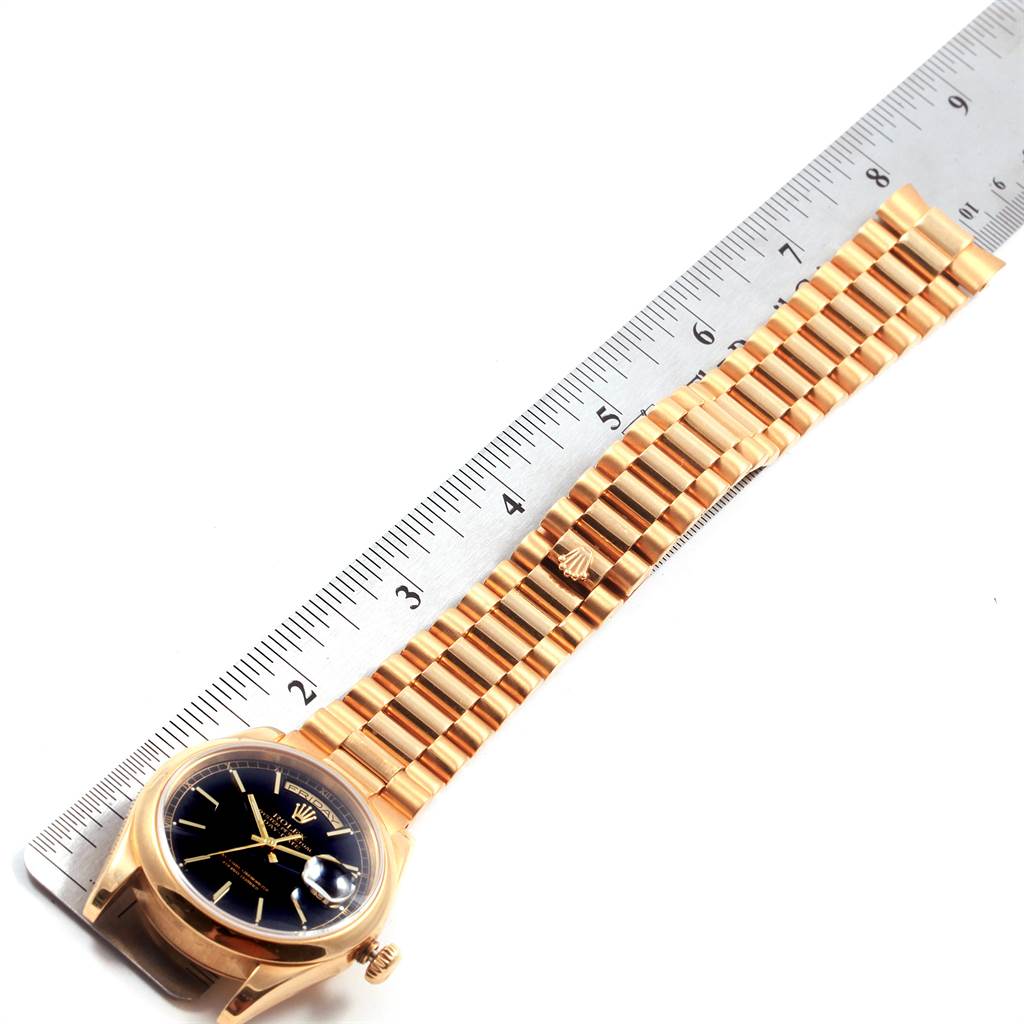 This image shows a Rolex President 118208 Men
s Yellow Gold Black Dial 118208 Men
s Yellow Gold Black Dial model watch with a gold band, placed next to a ruler for measurement.