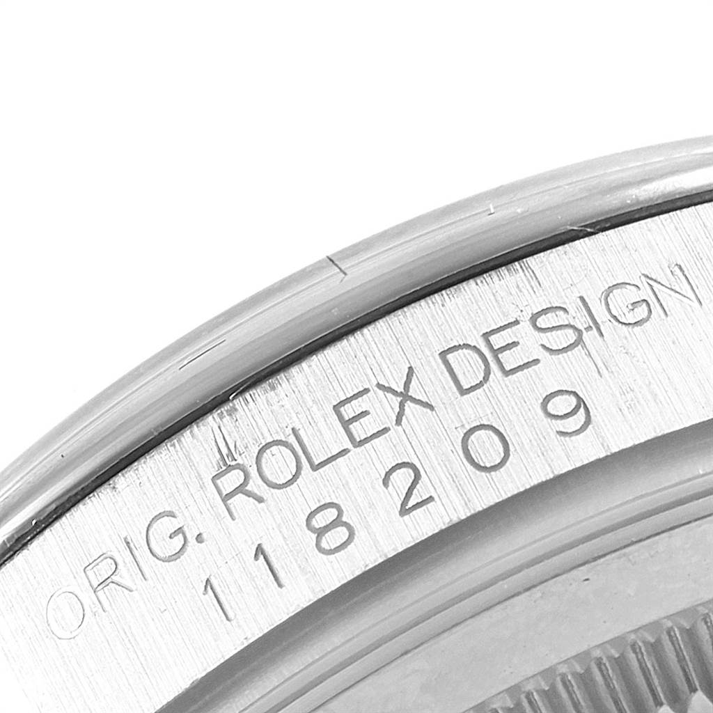 This close-up image of the Rolex President 118209 Men's White Gold Black Dial 118209 Men's White Gold Black Dial watch shows the engraved model number and the "Rolex Design" text on its case side.