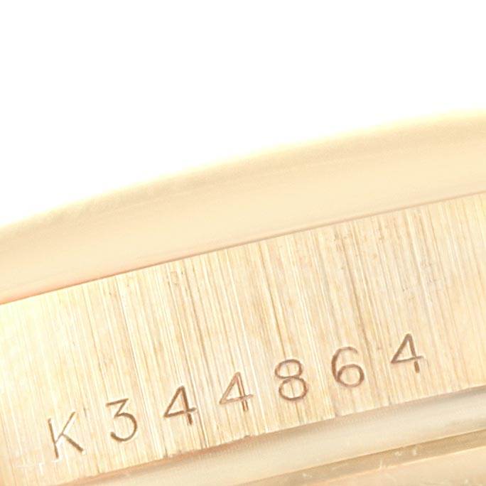 The image shows a close-up of the serial number engraved on the side of a Rolex President 118208 Men
s Yellow Gold Silver Dial 118208 Men
s Yellow Gold Silver Dial watch case.