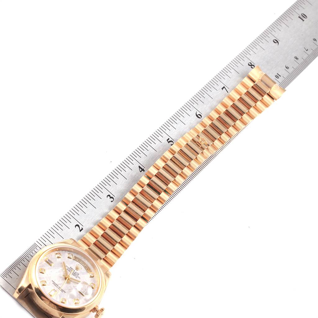 The image shows a Rolex President 118208 Men
s Yellow Gold Silver Dial 118208 Men
s Yellow Gold Silver Dial model watch laid flat with its band alongside a ruler for measurement.