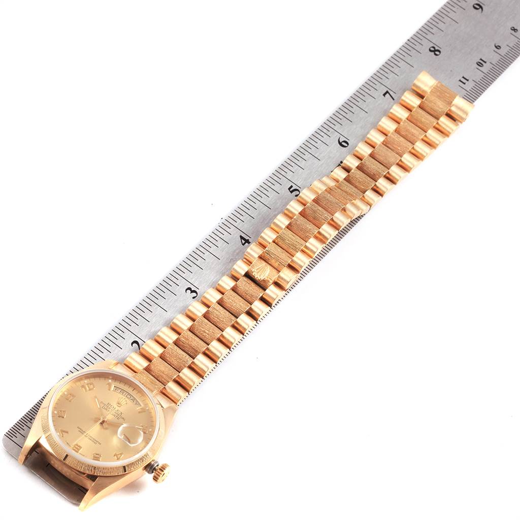 The image shows a Rolex President 18078 Men
s Yellow Gold Champagne Dial 18078 Men
s Yellow Gold Champagne Dial model watch lying flat with a ruler, displaying its face, crown, and bracelet in full view.
