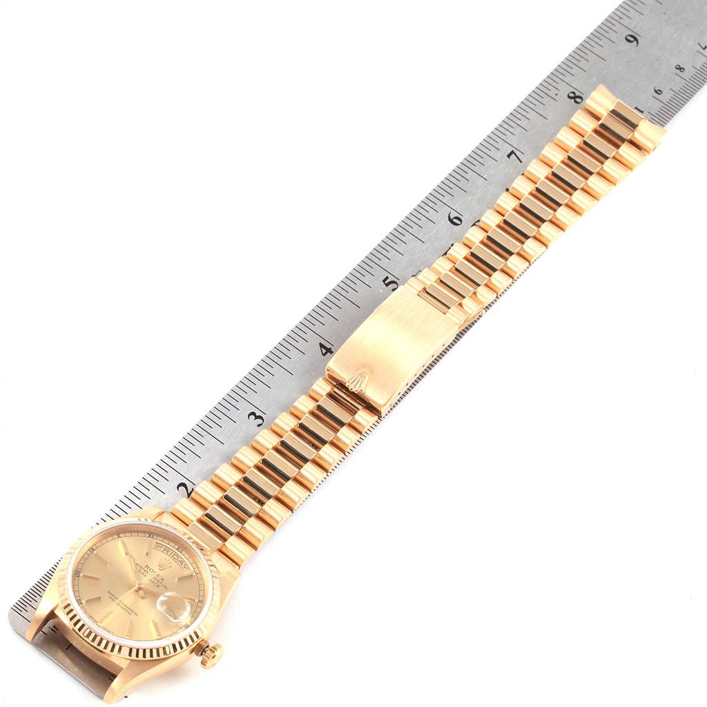 The image shows a top-down view of a Rolex President 18238 Men
s Yellow Gold Champagne Dial 18238 Men
s Yellow Gold Champagne Dial model watch and its gold bracelet, placed alongside a ruler for scale.