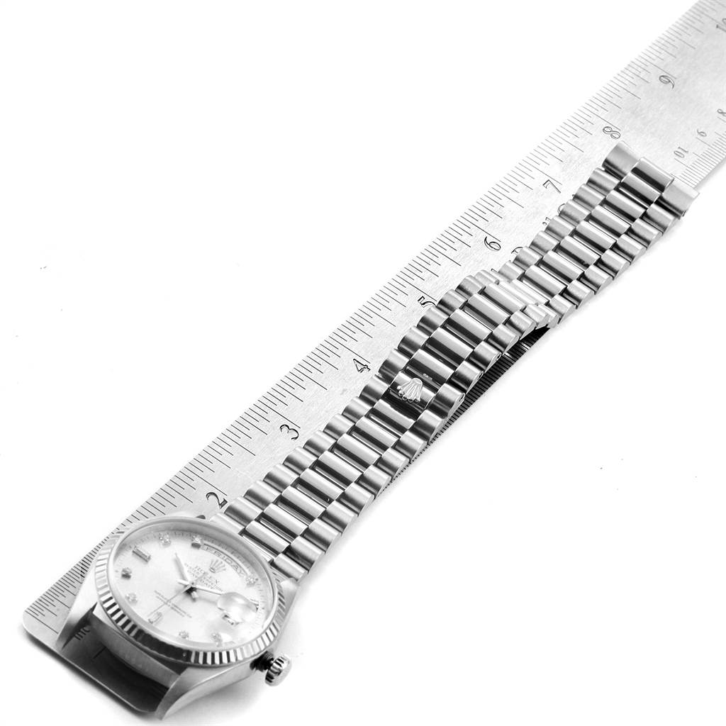 The Rolex President 18239 Men's White Gold Silver Dial 18239 Men's White Gold Silver Dial model watch is shown from a top-down angle alongside a ruler, highlighting its bezel, dial, and bracelet.