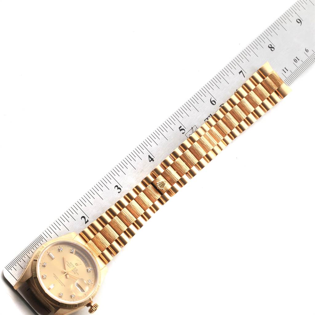 The Rolex President 18248 Men
s Yellow Gold Champagne Dial 18248 Men
s Yellow Gold Champagne Dial model watch is shown in a flat lay, highlighting its bracelet next to a ruler.