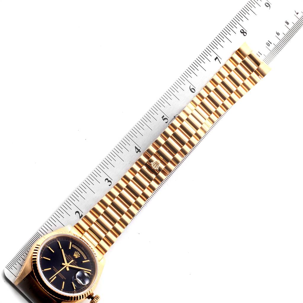 The image shows a Rolex President 18238 Men
s Yellow Gold Black Dial 18238 Men
s Yellow Gold Black Dial watch placed alongside a ruler, highlighting its length and gold bracelet.