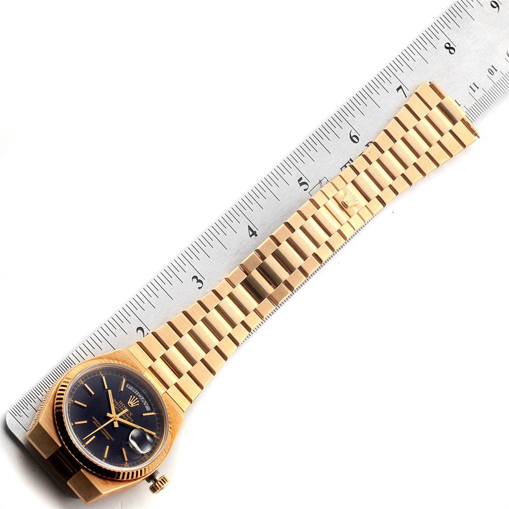 The image shows a gold Rolex President 19018 Men
s Yellow Gold Black Dial 19018 Men
s Yellow Gold Black Dial watch laid flat next to a ruler, highlighting the full watch and bracelet.