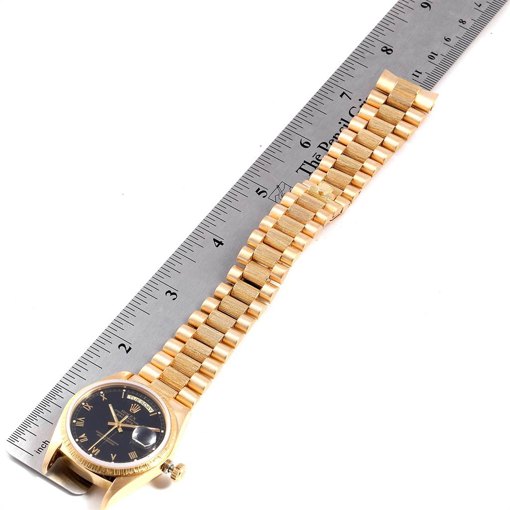 The watch is a Rolex President 18038 Men
s Yellow Gold Black Dial 18038 Men
s Yellow Gold Black Dial model, shown from a top view featuring its face and bracelet aligned with a ruler for scale.