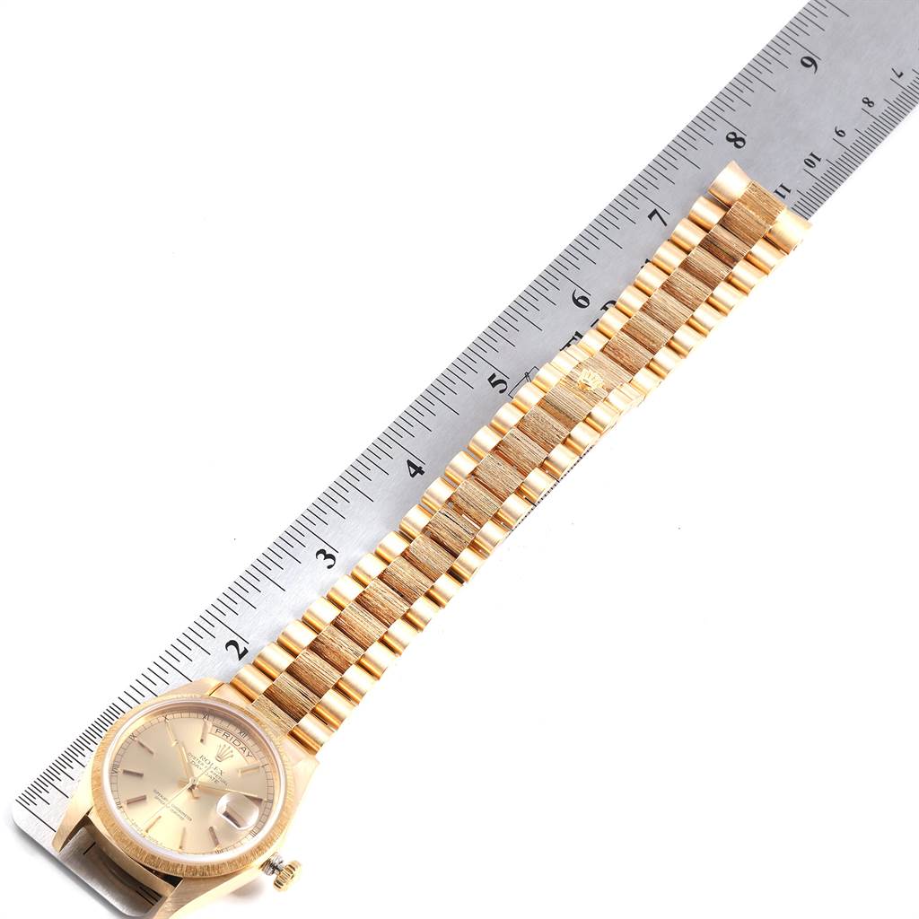 The image shows a Rolex President 18078 Men
s Yellow Gold Champagne Dial 18078 Men
s Yellow Gold Champagne Dial model watch with a gold bracelet and part of the watch face, alongside a ruler.