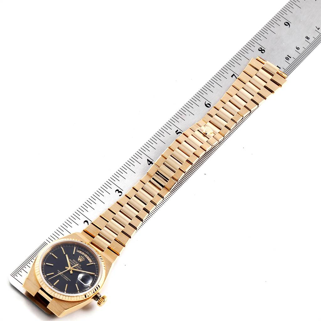 The Rolex President 19018 Men's Yellow Gold Black Dial 19018 Men's Yellow Gold Black Dial model watch is shown from the front, displaying the dial, bezel, and bracelet alongside a ruler for measurement.