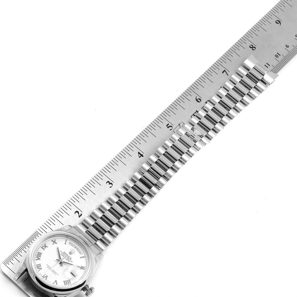 The image shows a Rolex President 118209 Men
s White Gold White Dial 118209 Men
s White Gold White Dial model watch with its bracelet extended next to a ruler for measurement.