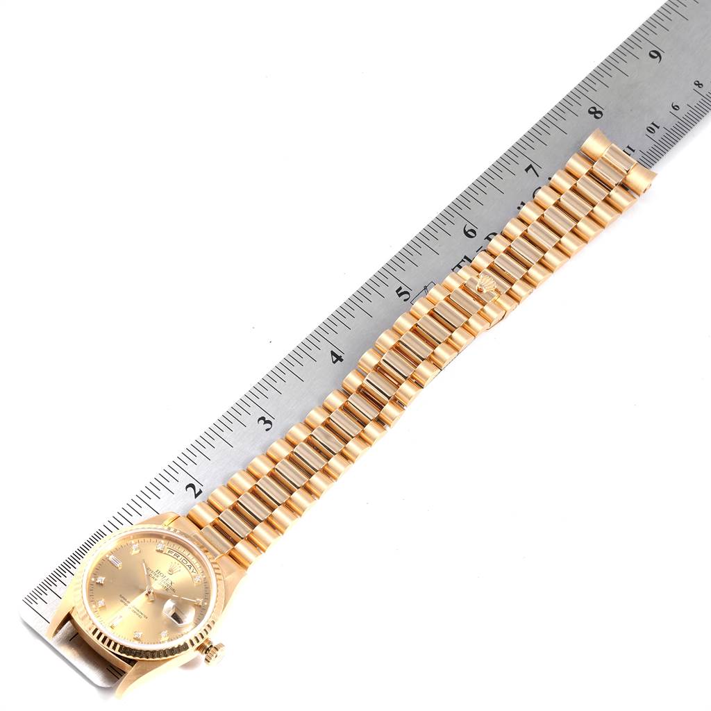 This image shows a Rolex President 18238 Men
s Yellow Gold Champagne Dial 18238 Men
s Yellow Gold Champagne Dial model watch laid flat alongside a ruler, showcasing the band and watch face.