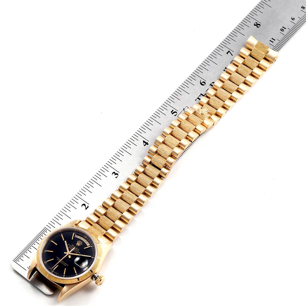 The image shows a Rolex President 18078 Men
s Yellow Gold Black Dial 18078 Men
s Yellow Gold Black Dial model watch laid flat with its gold band against a ruler, displaying its length.