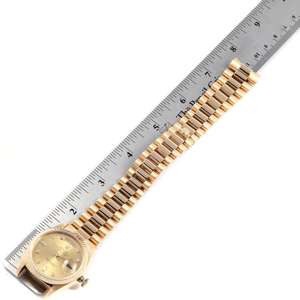 The image shows a Rolex President 18038 Men's Yellow Gold Champagne Dial 18038 Men's Yellow Gold Champagne Dial model watch laying next to a ruler, highlighting its strap and face.