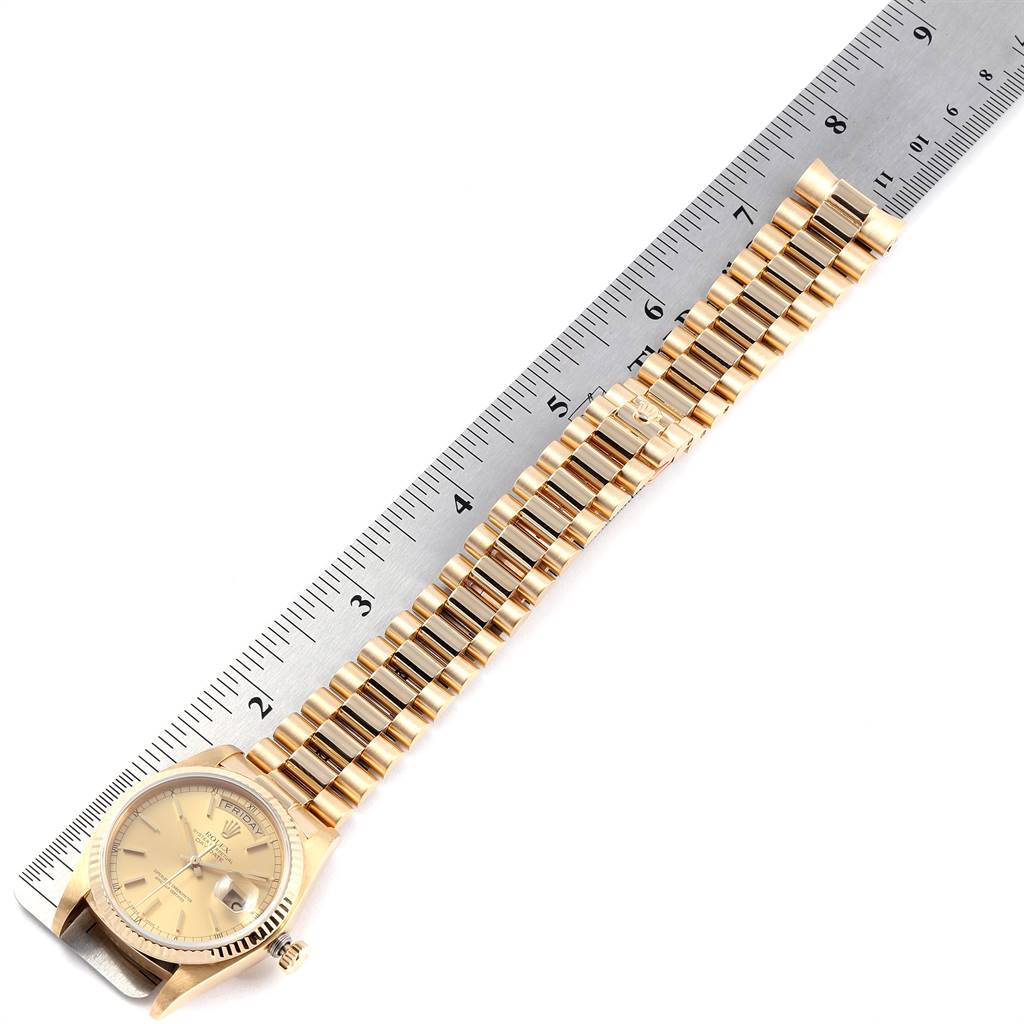 The Rolex President 18038 Men
s Yellow Gold Champagne Dial 18038 Men
s Yellow Gold Champagne Dial model watch is shown from an overhead angle with its gold bracelet extended alongside a ruler.