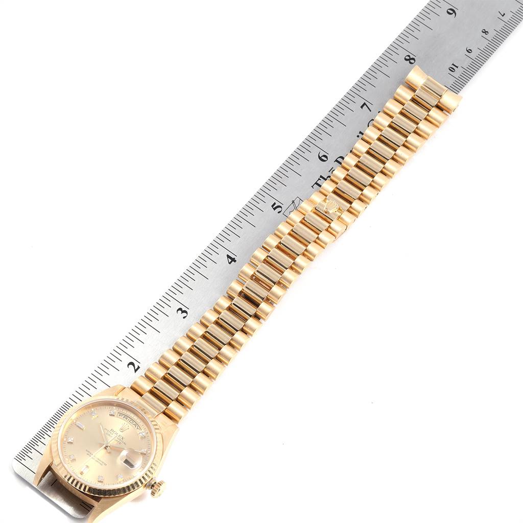 The image shows a top view of a Rolex President 18238 Men
s Yellow Gold Champagne Dial 18238 Men
s Yellow Gold Champagne Dial model watch, displaying its face and bracelet next to a ruler for scale.