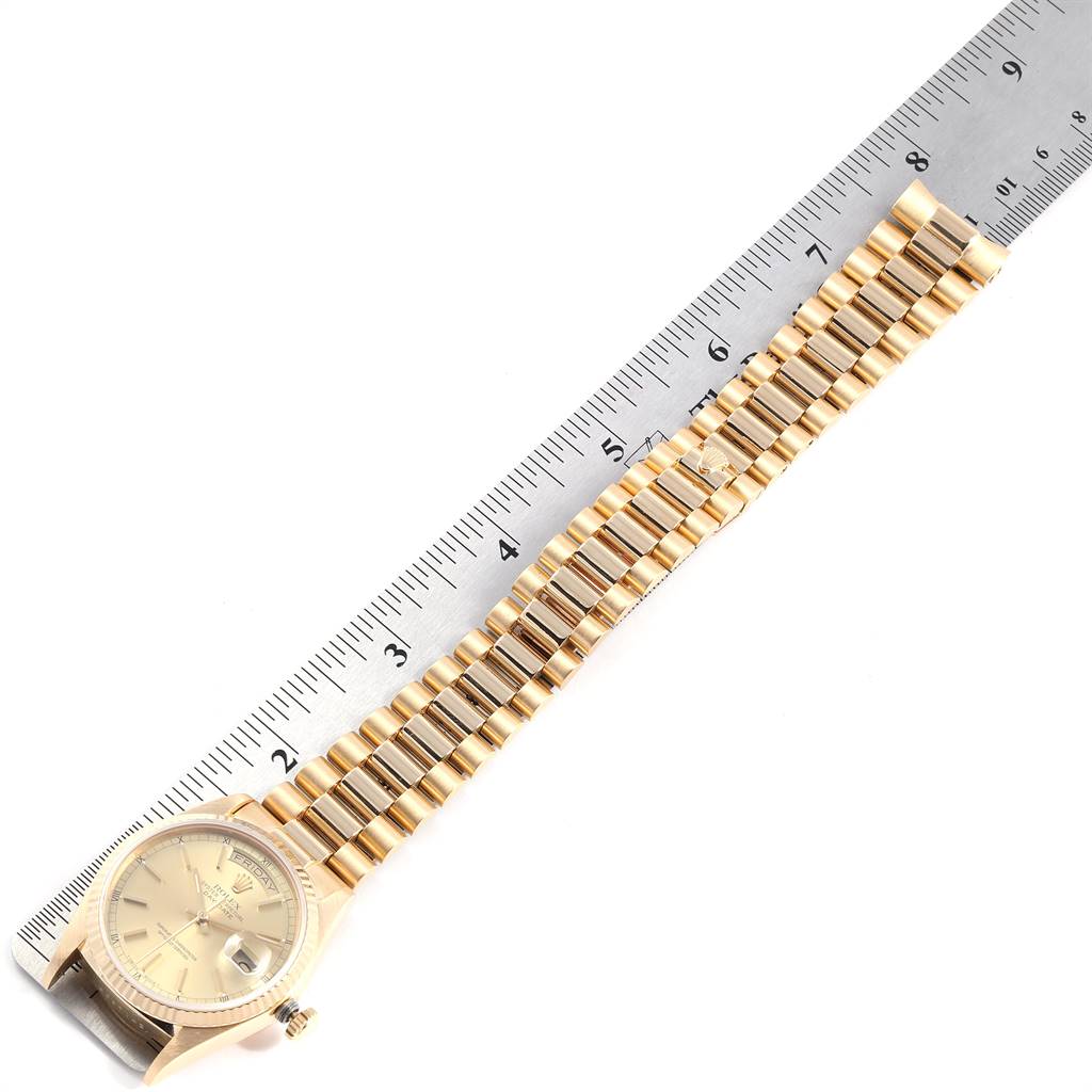 This image shows a Rolex President 18038 Men
s Yellow Gold Champagne Dial 18038 Men
s Yellow Gold Champagne Dial model watch with its gold bracelet extended next to a ruler for measurement.