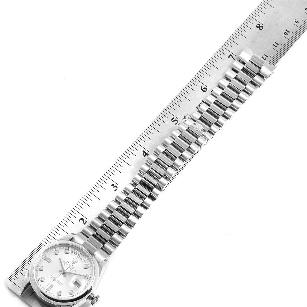 The image shows a top view of the Rolex President 118209 Men's White Gold Silver Dial 118209 Men's White Gold Silver Dial watch, with its band aligned next to a ruler.