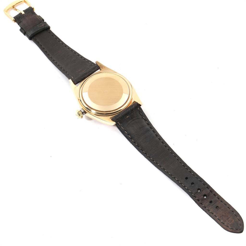 The image shows the back of a Rolex President 1803 Men's Yellow Gold Champagne Dial 1803 Men's Yellow Gold Champagne Dial model watch with a black leather strap and gold case.