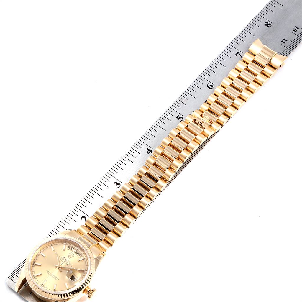 The Rolex President 118238 Men
s Yellow Gold Champagne Dial 118238 Men
s Yellow Gold Champagne Dial model watch is shown from a top-down angle, with both the face and the bracelet displayed alongside a ruler.