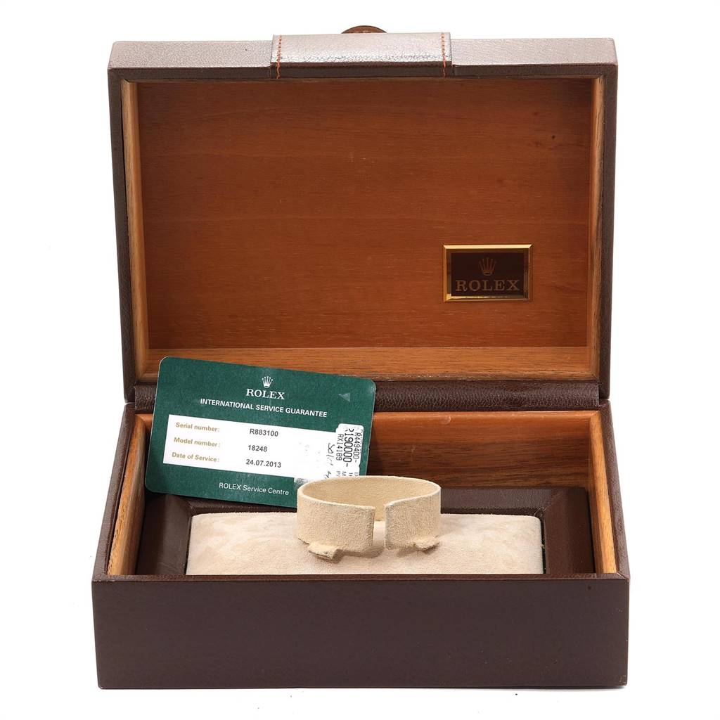 The image shows an open Rolex watch box for the President model, with a green service card and a beige watch holder inside.