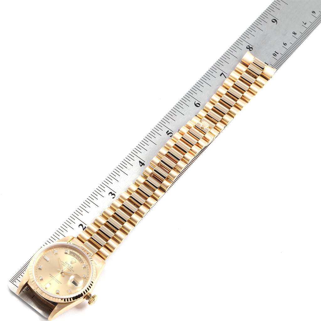 The image shows the President model Rolex watch laid flat next to a ruler, highlighting the bracelet and face.