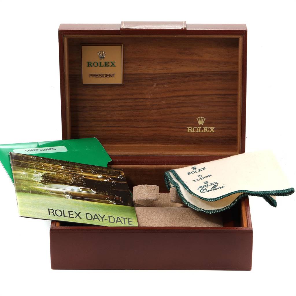 Shown is an open Rolex President 18038 Men
s Yellow Gold Black Dial 18038 Men
s Yellow Gold Black Dial watch box with manuals, a cleaning cloth, and cushion in an upright angle.