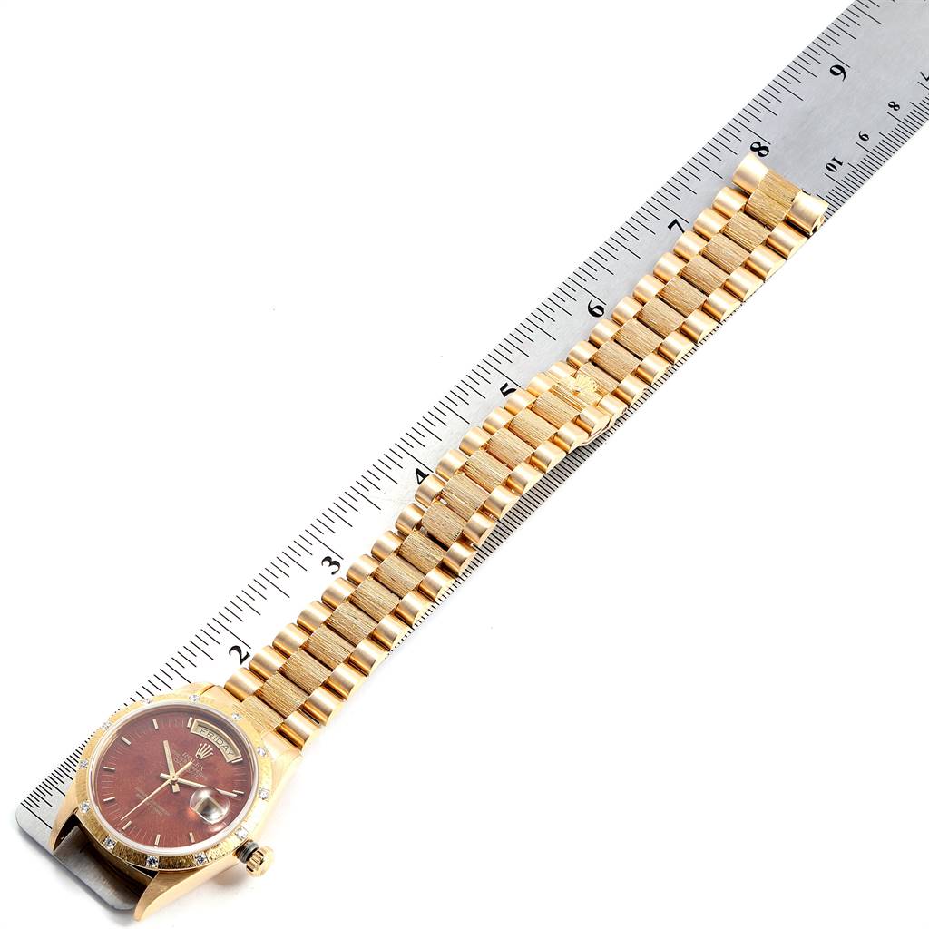 The image shows a Rolex President 18108 Men
s Yellow Gold Brown Dial 18108 Men
s Yellow Gold Brown Dial model watch and its bracelet lying flat alongside a ruler for measurement.