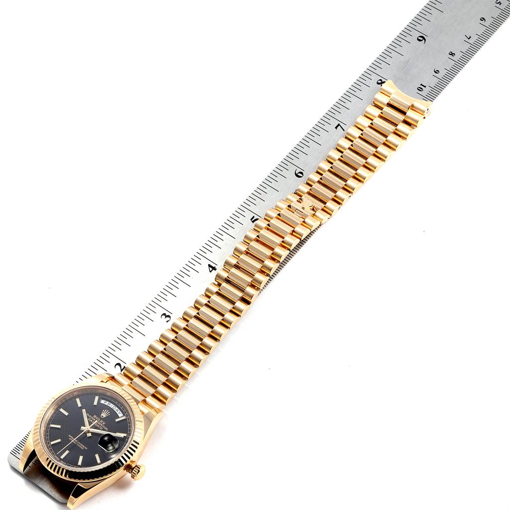 The image shows a Rolex President 228238 Men
s Yellow Gold Black Dial 228238 Men
s Yellow Gold Black Dial model watch laid flat with its gold bracelet and face visible alongside a ruler for measurement.