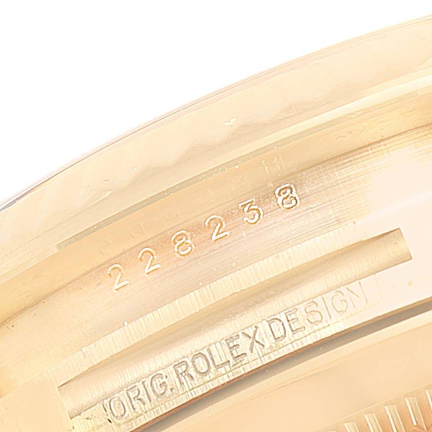The image shows the engraved side of the bezel of a Rolex President 228238 Men
s Yellow Gold Black Dial 228238 Men
s Yellow Gold Black Dial model watch, displaying its serial number and "ORIG ROLEX DESIGN" inscription.