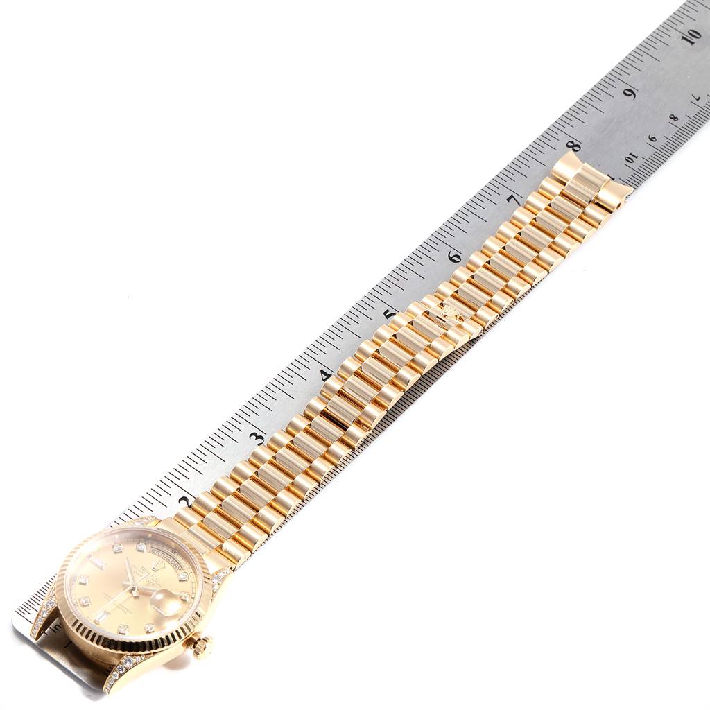 This image shows a top view of a Rolex President 118338 Men's Yellow Gold Champagne Dial 118338 Men's Yellow Gold Champagne Dial model watch with its gold bracelet next to a ruler.