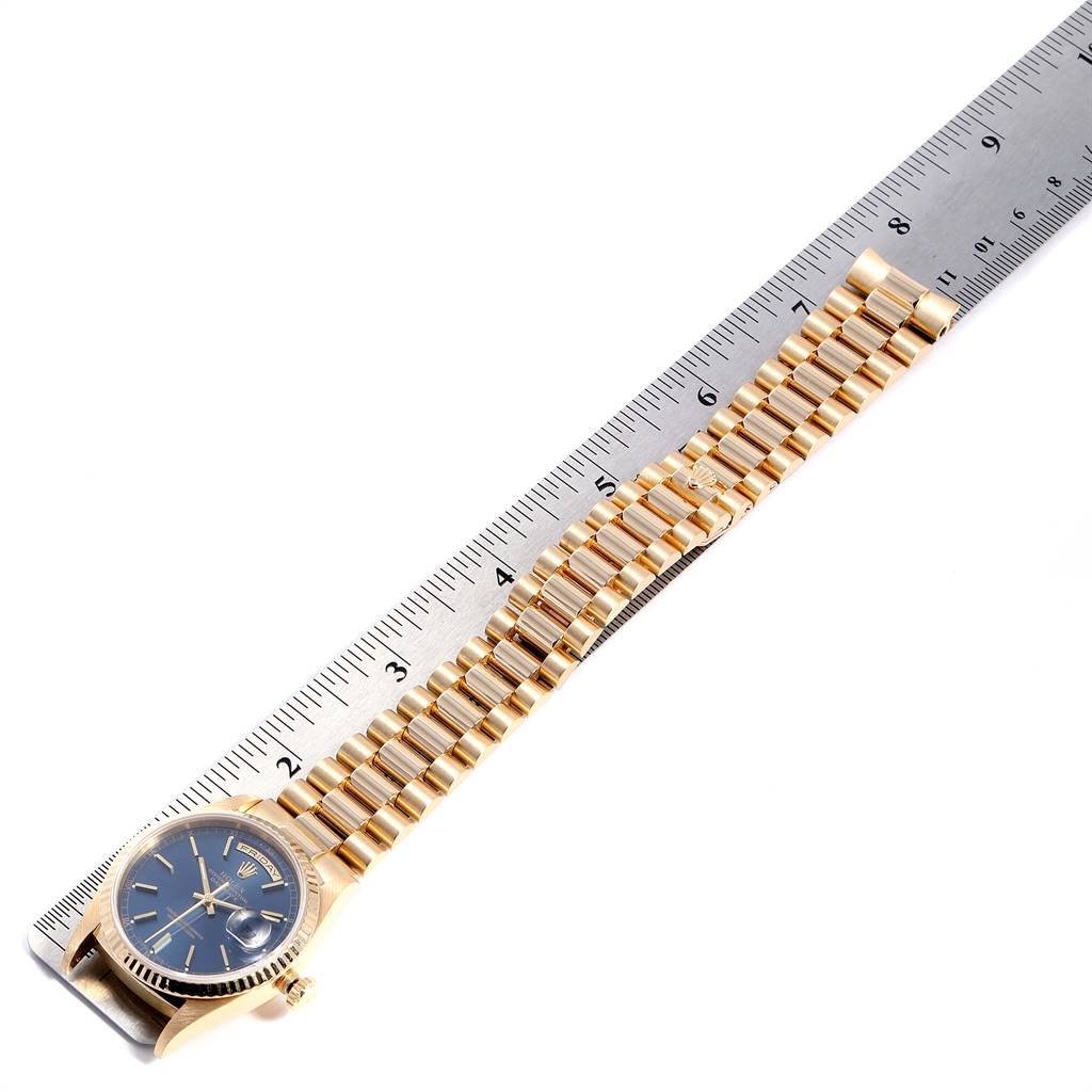 The image shows a Rolex President 18238 Men
s Yellow Gold Blue Dial 18238 Men
s Yellow Gold Blue Dial model watch laid flat next to a ruler, displaying the case and gold bracelet from an overhead angle.