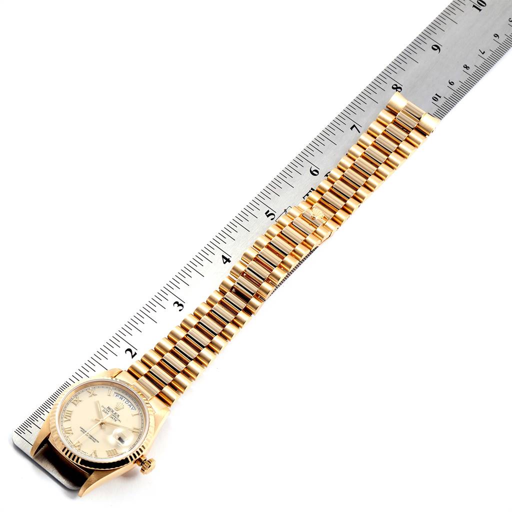 This image shows a Rolex President 18238 Men
s Yellow Gold Beige Dial 18238 Men
s Yellow Gold Beige Dial watch face-up with its band extended and placed alongside a ruler for measurement.