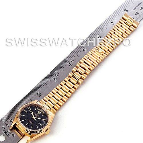 The image shows a Rolex President 18038 Men's Yellow Gold Black Dial 18038 Men's Yellow Gold Black Dial model watch laid flat next to a ruler, highlighting the gold bracelet and the black dial.