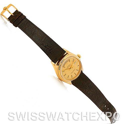 This image shows a Rolex President 1803 Men's Yellow Gold Champagne Dial 1803 Men's Yellow Gold Champagne Dial model watch with a gold case and a dark leather strap, viewed from an angled top-down perspective.