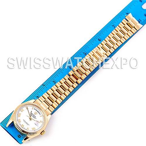 This image shows an overhead view of a Rolex President 118238 Men's Yellow Gold White Dial 118238 Men's Yellow Gold White Dial watch, including its face, band, and part of the clasp, placed next to a blue ruler.